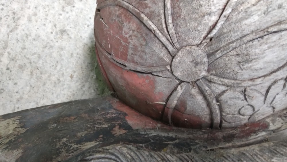 A weathered hand-carved wooden Chinese guardian lion resting its front paw on a decorative brocade ball. View VII