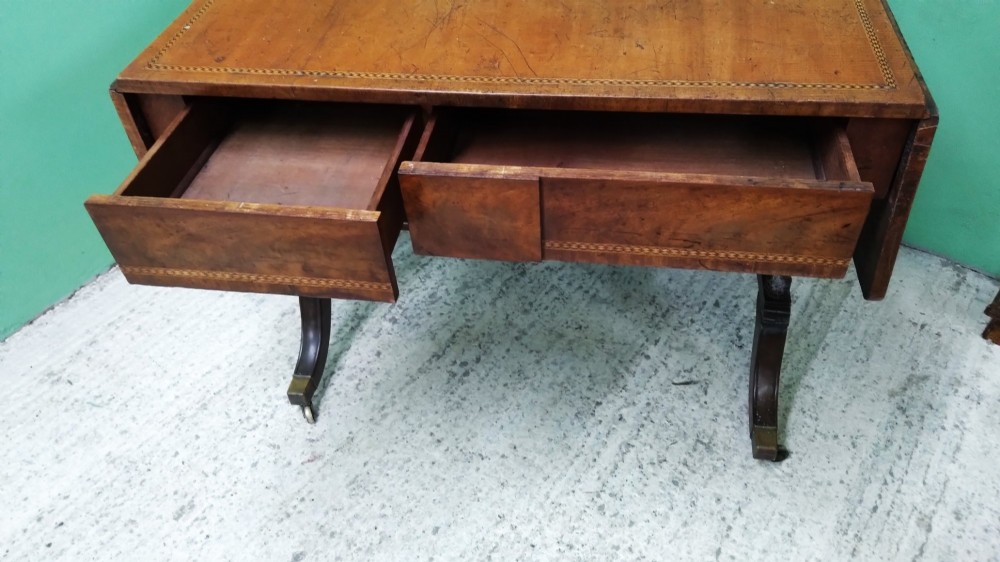 A George III mahogany drop-leaf sofa table featuring decorative border string inlay, two front drawers, a turned stretcher, and splayed legs fitted with brass castors. View VII