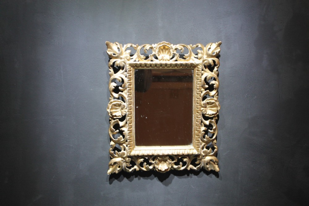 A 19th-century Florentine wall mirror featuring an ornate, pierced giltwood frame decorated with openwork scrollwork and shell carving.