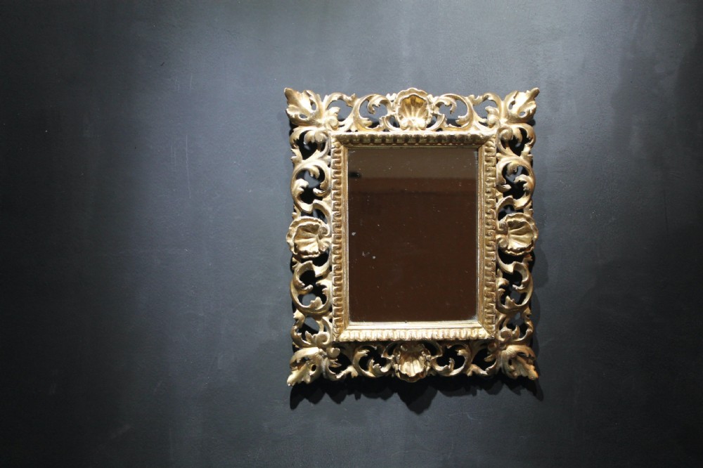 A 19th-century Florentine wall mirror featuring an ornate, pierced giltwood frame decorated with openwork scrollwork and shell carving. View II