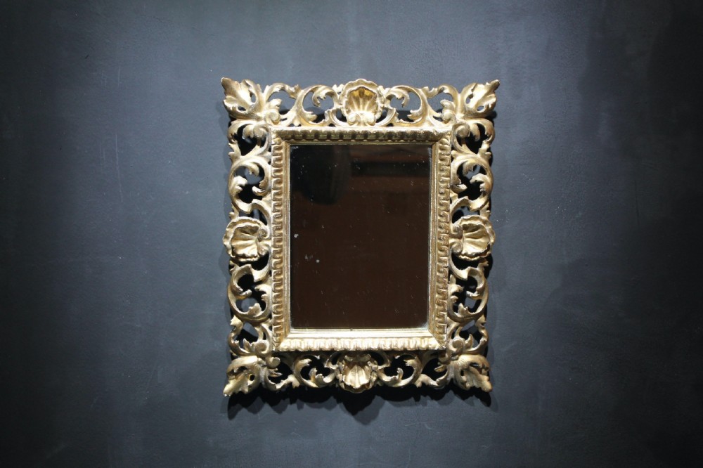 A 19th-century Florentine wall mirror featuring an ornate, pierced giltwood frame decorated with openwork scrollwork and shell carving. View III