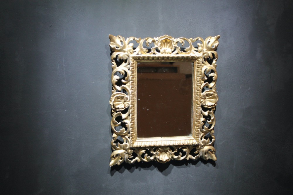 A 19th-century Florentine wall mirror featuring an ornate, pierced giltwood frame decorated with openwork scrollwork and shell carving. View IV