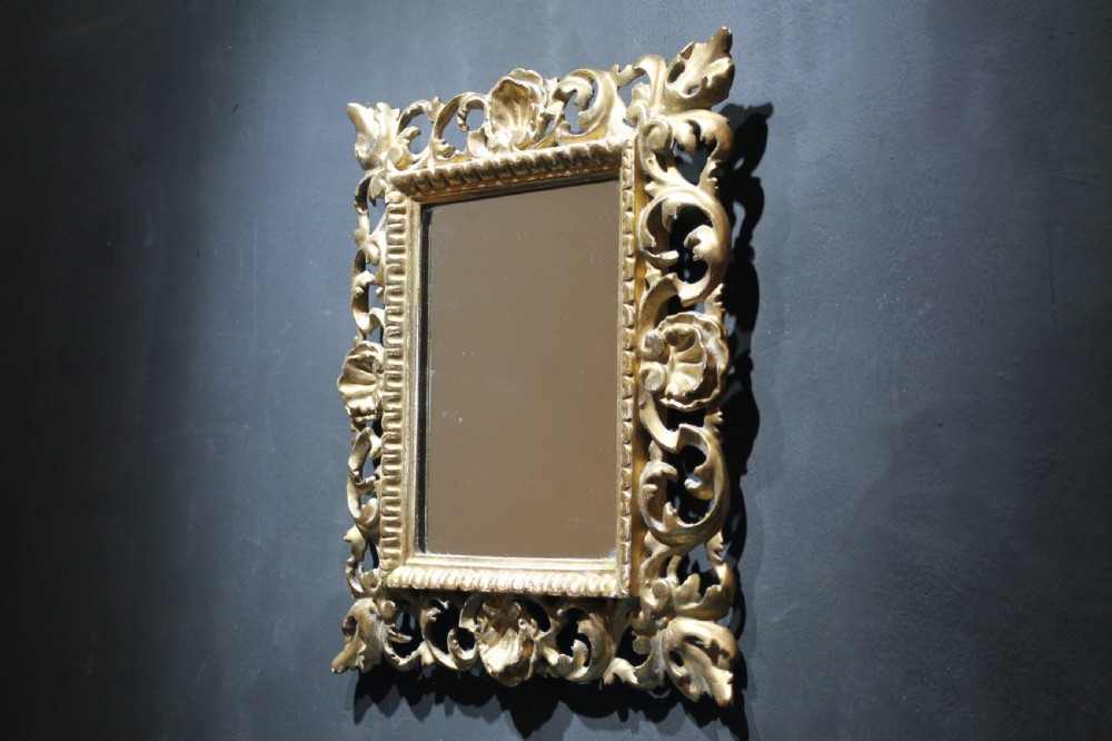 A 19th-century Florentine wall mirror featuring an ornate, pierced giltwood frame decorated with openwork scrollwork and shell carving. View V