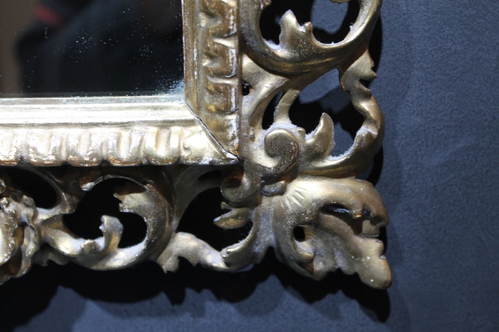 A 19th-century Florentine wall mirror featuring an ornate, pierced giltwood frame decorated with openwork scrollwork and shell carving. View VIII