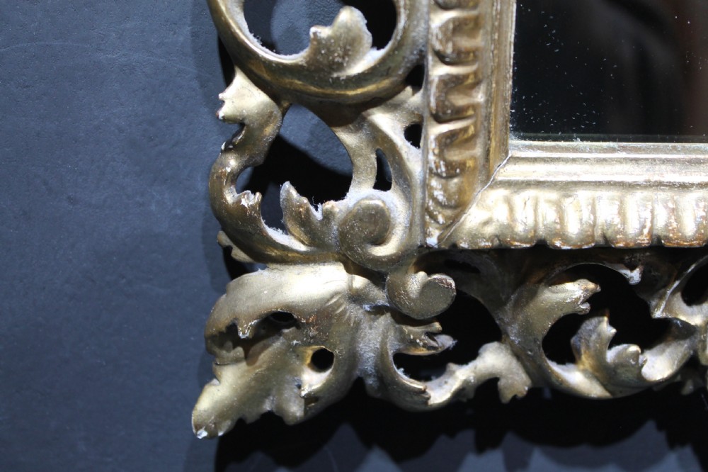 A 19th-century Florentine wall mirror featuring an ornate, pierced giltwood frame decorated with openwork scrollwork and shell carving. View IX