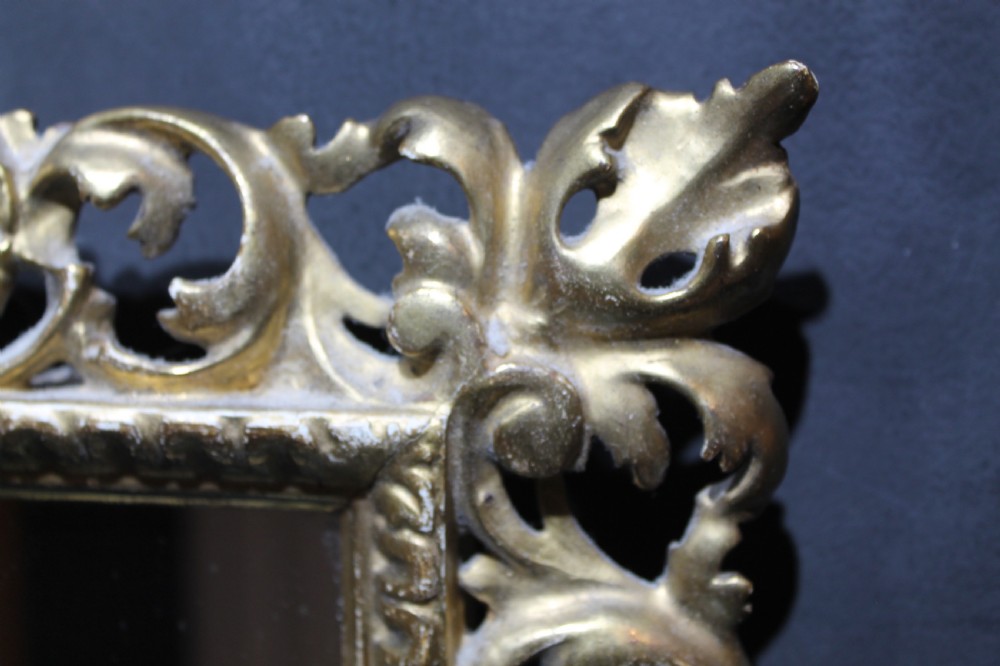 A 19th-century Florentine wall mirror featuring an ornate, pierced giltwood frame decorated with openwork scrollwork and shell carving. View XI