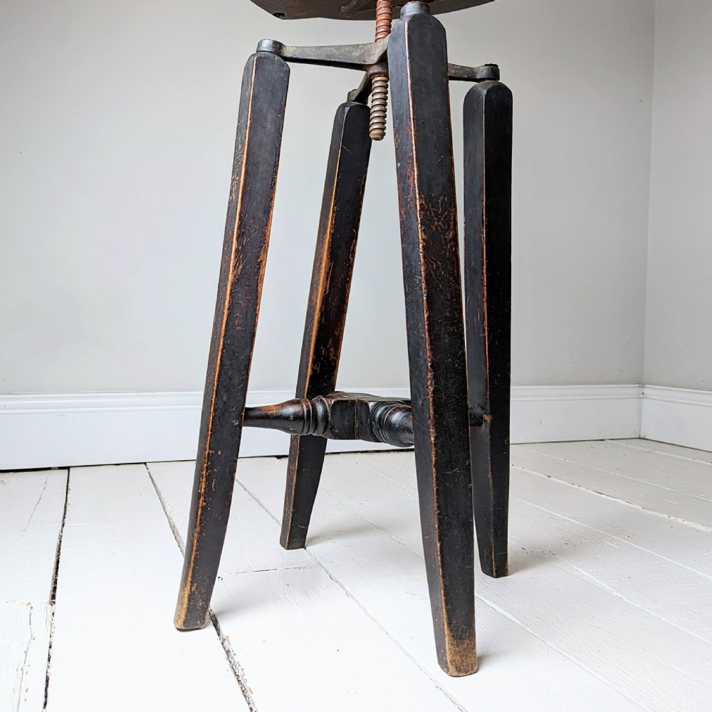 An antique dark wood childs barber chair featuring a swivel seat with a pierced pattern, curved arms, and a cast iron screw adjustment mechanism above splayed turned legs. View VIII