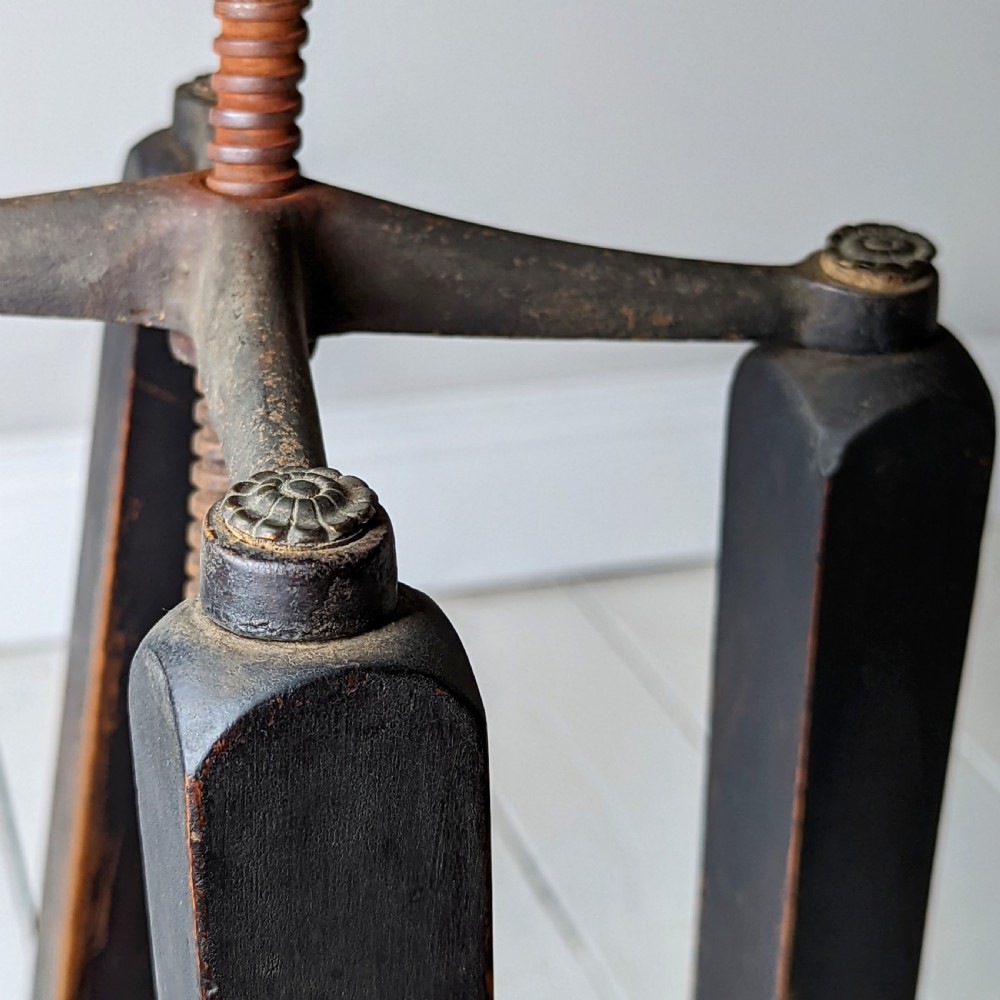 An antique dark wood childs barber chair featuring a swivel seat with a pierced pattern, curved arms, and a cast iron screw adjustment mechanism above splayed turned legs. View X