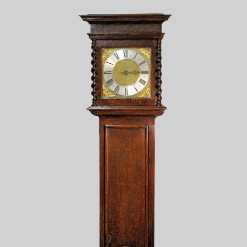 fig 1. A late 17th-century dark oak longcase clock hood featuring barley twist columns, carved frieze moulding, and a square brass dial.