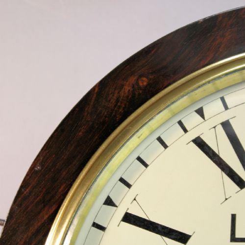 fig 3. A circular Victorian wall clock featuring a dark rosewood drum case, a polished brass bezel, and a cream painted dial signed L. Morris Islington with black Roman numerals.