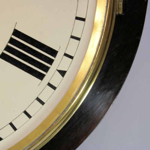 fig 4. A circular Victorian wall clock featuring a dark rosewood drum case, a polished brass bezel, and a cream painted dial signed L. Morris Islington with black Roman numerals.