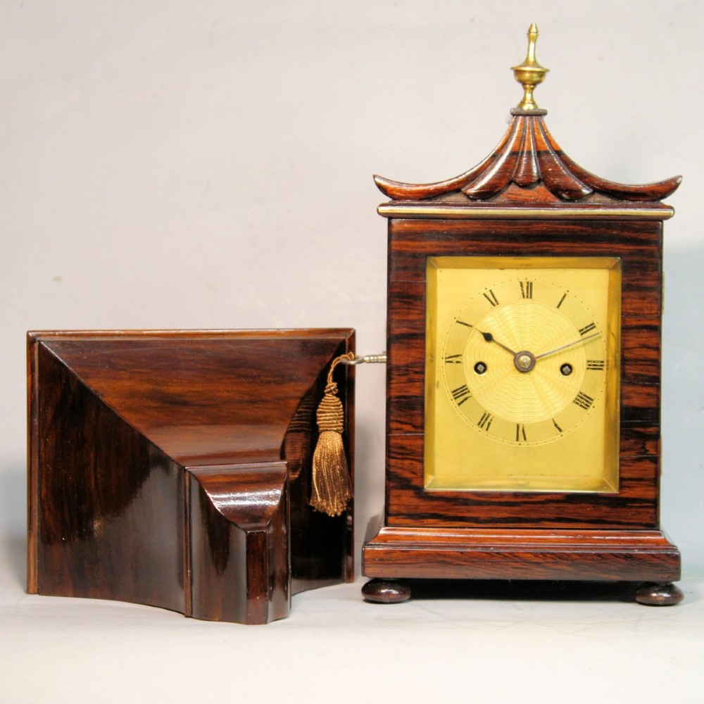 A Victorian rosewood miniature bracket clock featuring a pagoda roof, brass finial, and engine-turned brass dial alongside a matching carved rosewood wall bracket.