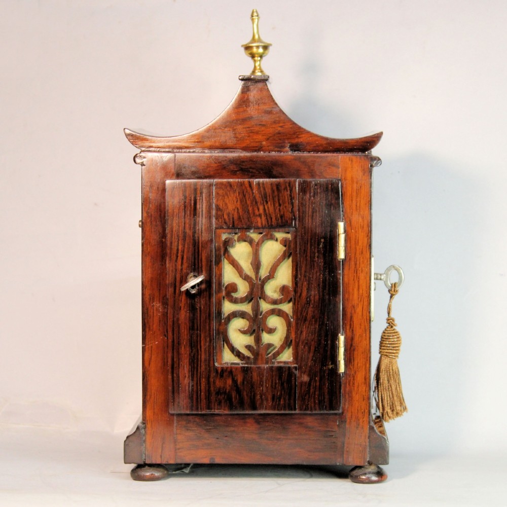 A Victorian rosewood miniature bracket clock featuring a pagoda roof, brass finial, and engine-turned brass dial alongside a matching carved rosewood wall bracket. View VIII