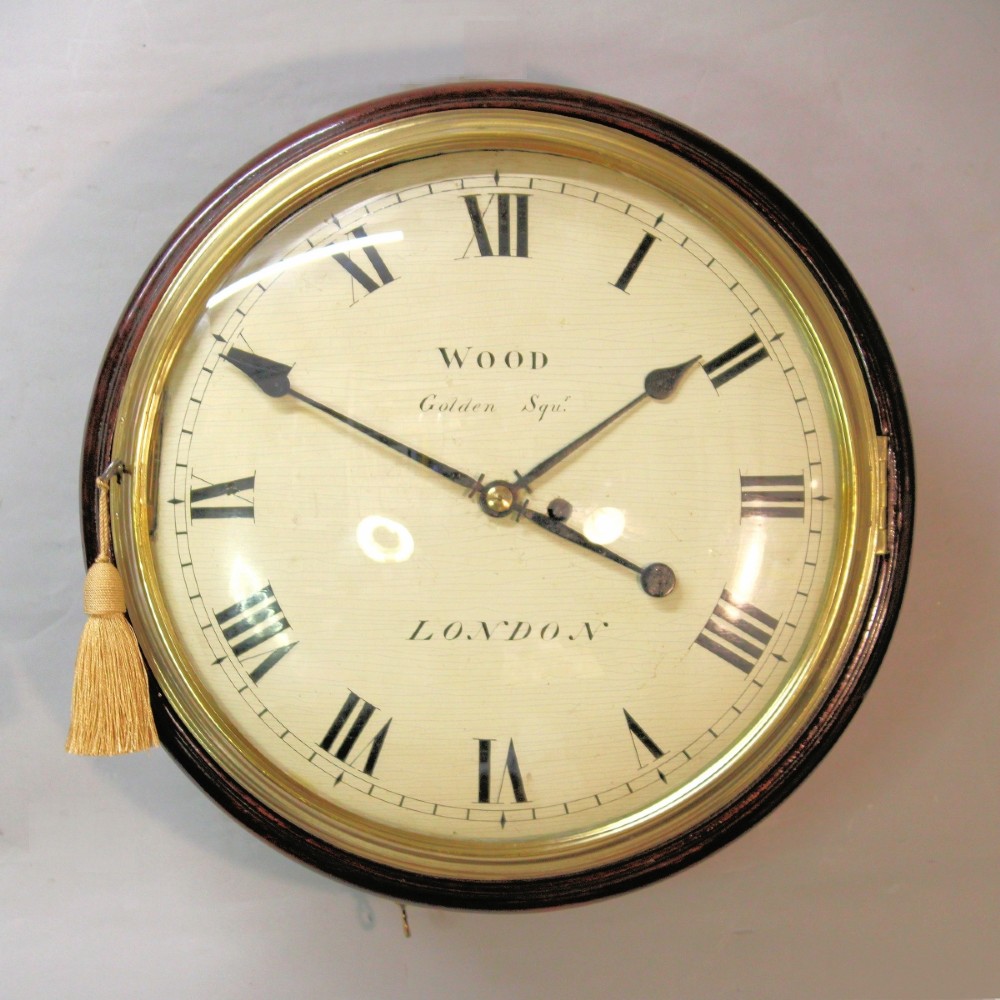An antique Regency single fusee wall clock featuring an off-white convex wooden dial with Roman numerals, brass bezel, and a dark polished mahogany surround.