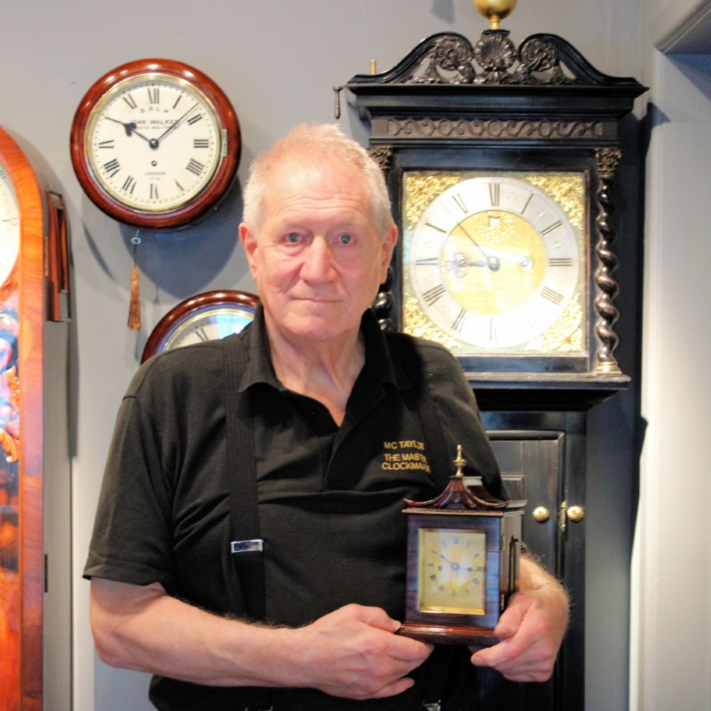 A Victorian rosewood miniature bracket clock featuring a pagoda roof, brass finial, and engine-turned brass dial alongside a matching carved rosewood wall bracket. View XI