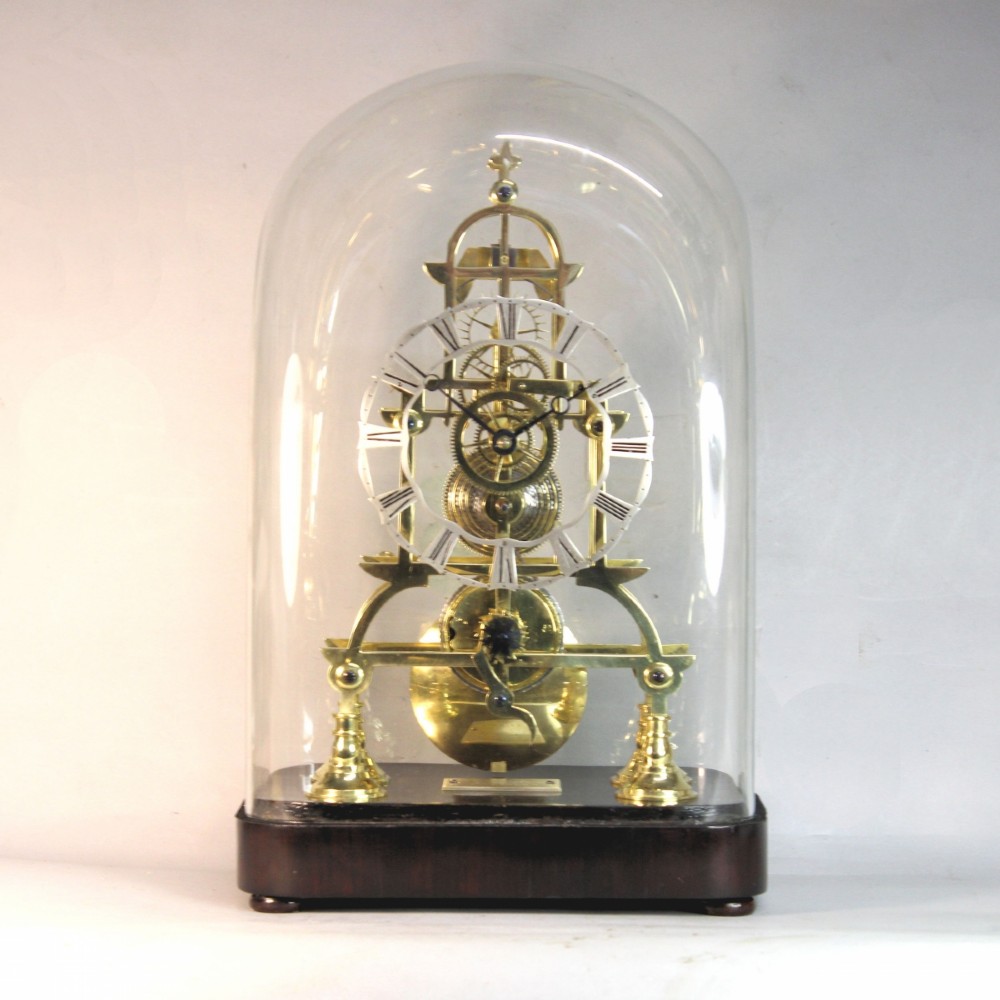 A Victorian brass skeleton clock featuring exposed internal gears, a silvered chapter ring, and a glass dome on a dark wooden base.