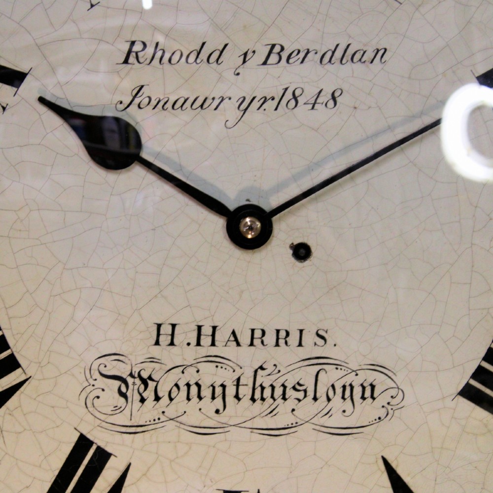 A circular Victorian wall clock featuring a dark mahogany surround, brass bezel, and cream painted dial with Roman numerals and black metal hands. View III