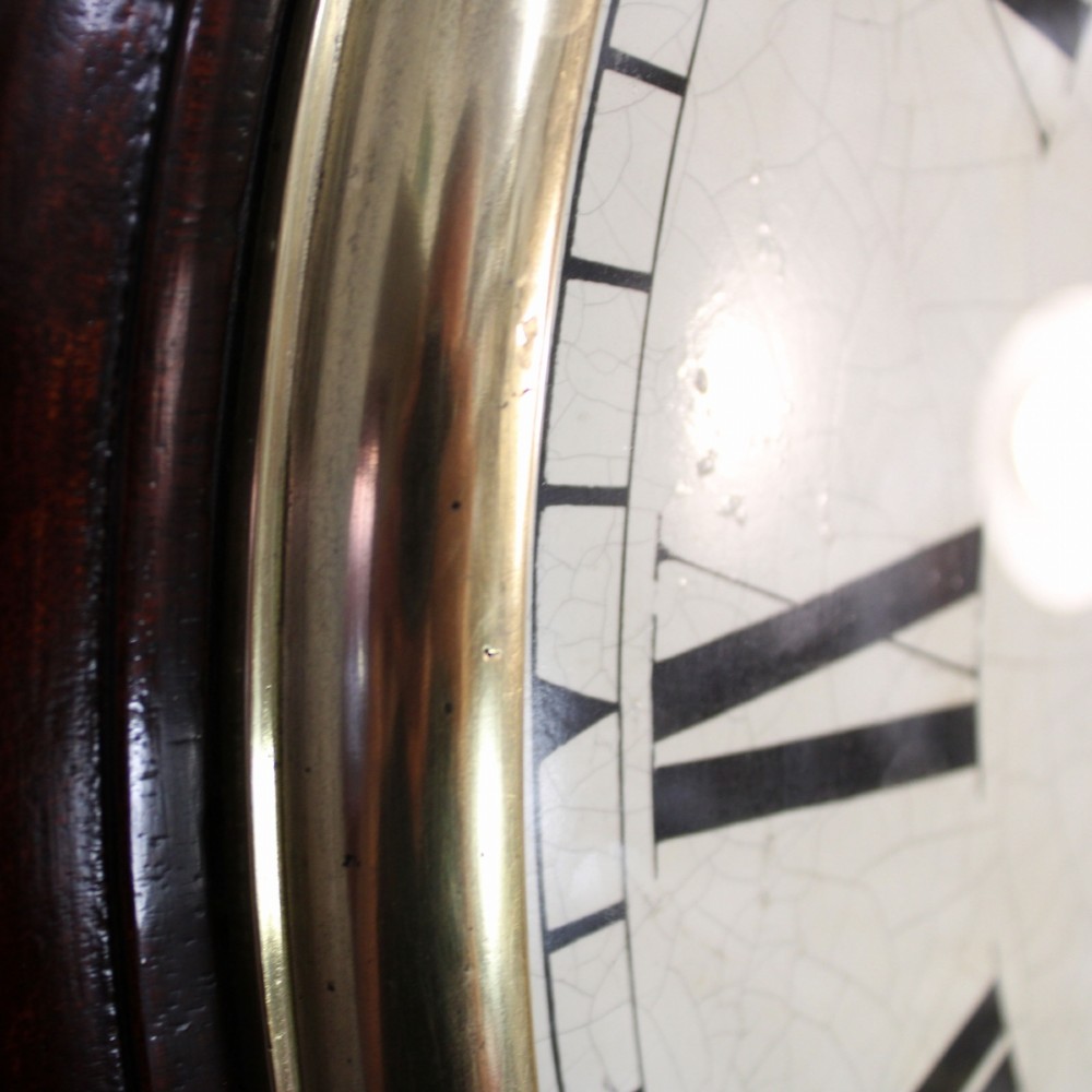 A circular Victorian wall clock featuring a dark mahogany surround, brass bezel, and cream painted dial with Roman numerals and black metal hands. View VI