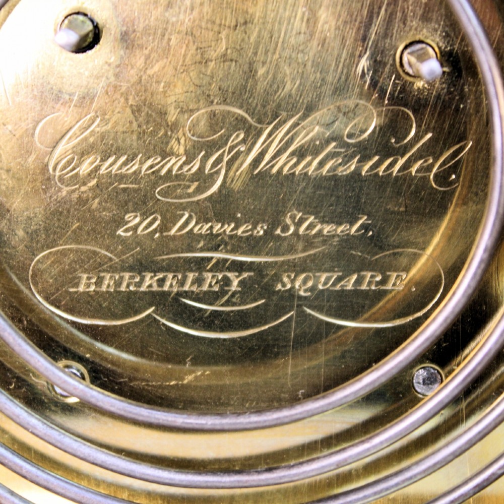 An ornate Victorian gilt brass carriage clock featuring detailed foliage engraving, corner columns, a decorative scroll handle, and a silvered sunburst dial with Roman numerals. View XI