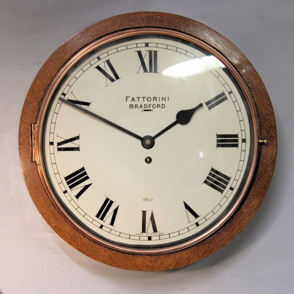 A circular twentieth-century oak wall dial clock with black Roman numerals on a cream face, inscribed Fattorini Bradford.
