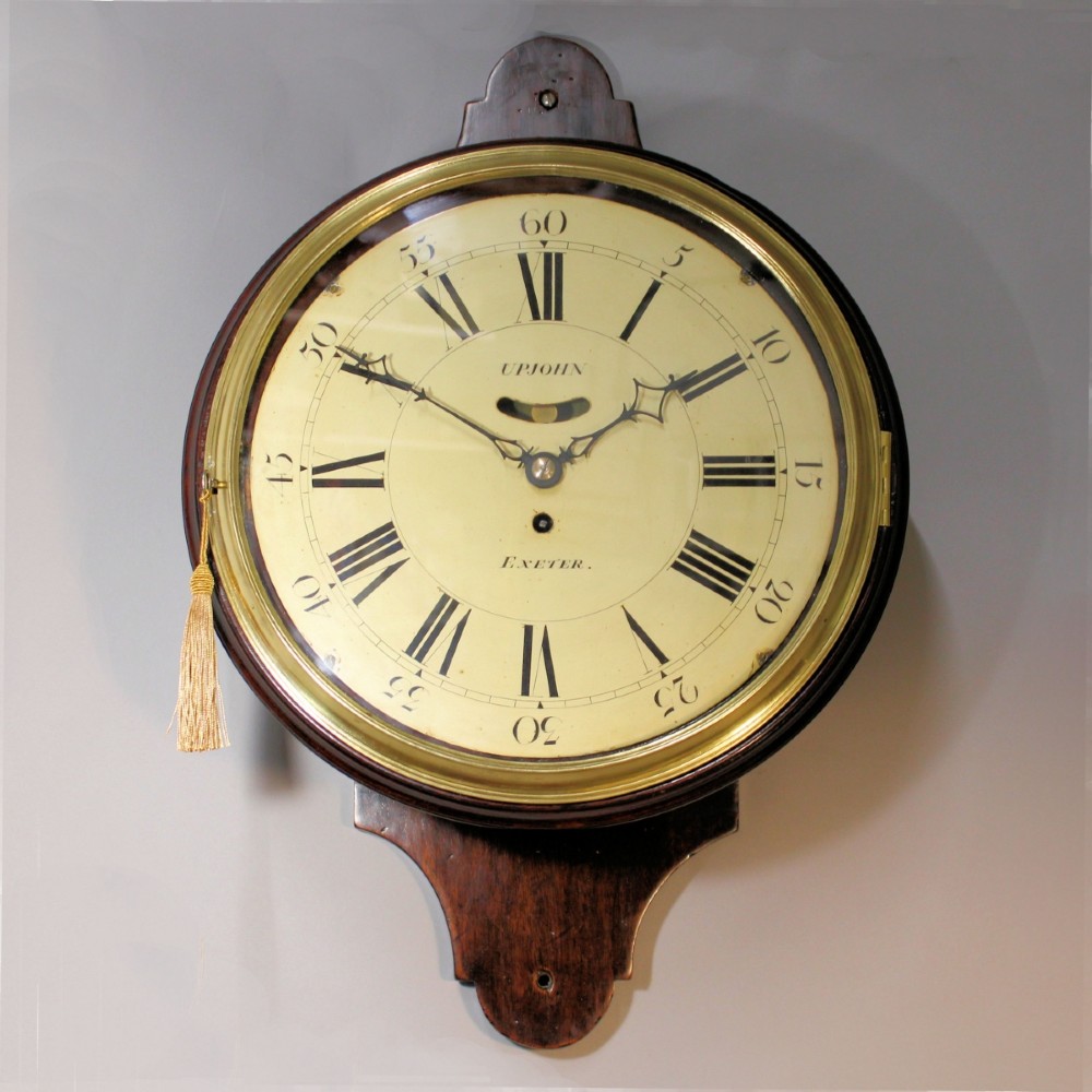 A late 18th-century Georgian mahogany wall clock featuring a circular cream painted dial with Roman numerals, a brass bezel, and a salt-box wooden case.