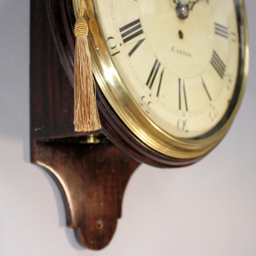 A late 18th-century Georgian mahogany wall clock featuring a circular cream painted dial with Roman numerals, a brass bezel, and a salt-box wooden case. View IV