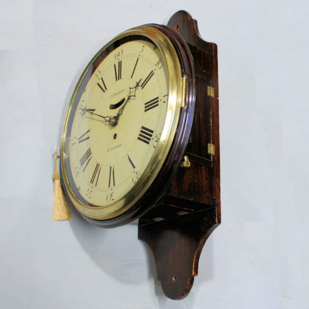 A late 18th-century Georgian mahogany wall clock featuring a circular cream painted dial with Roman numerals, a brass bezel, and a salt-box wooden case. View VI