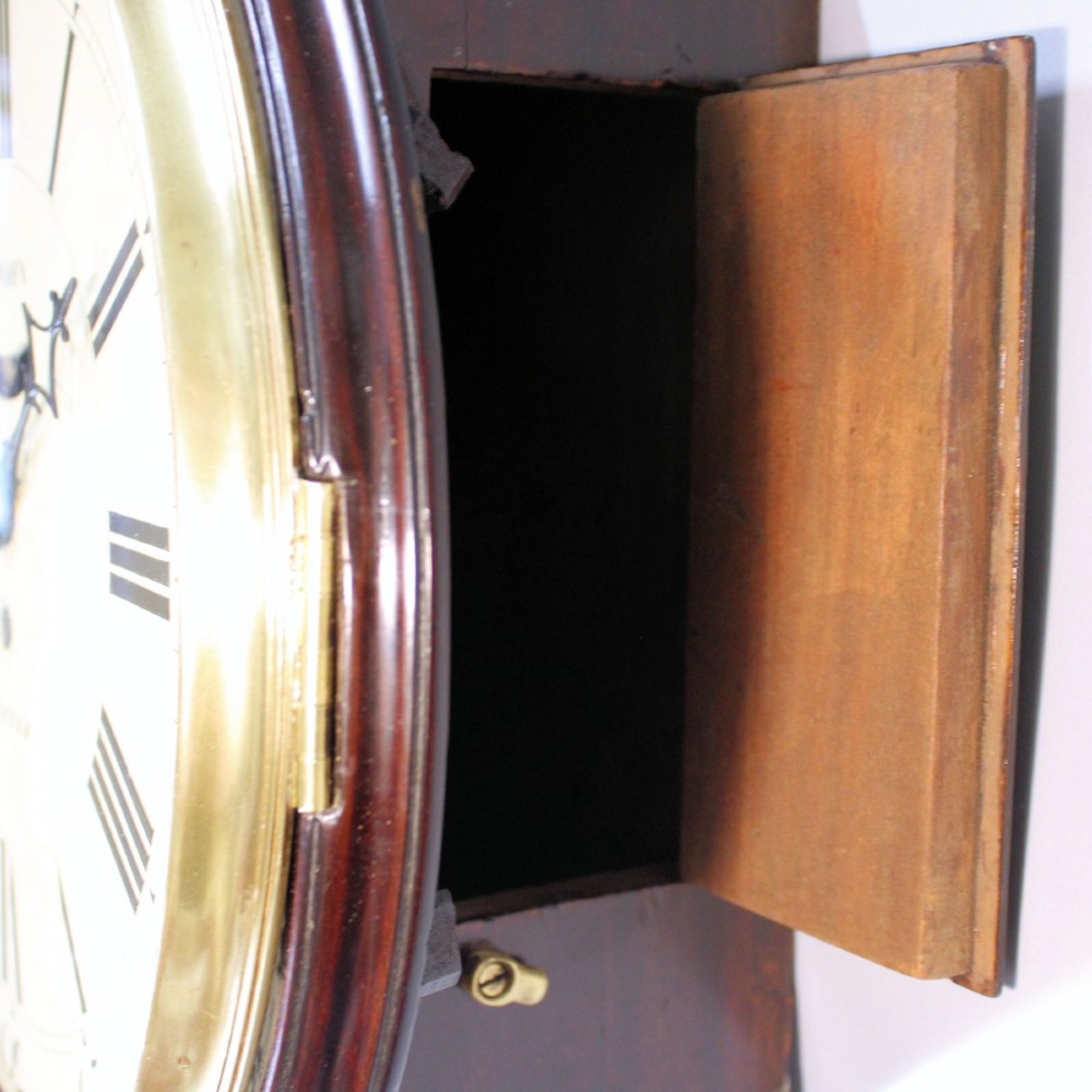A late 18th-century Georgian mahogany wall clock featuring a circular cream painted dial with Roman numerals, a brass bezel, and a salt-box wooden case. View VIII