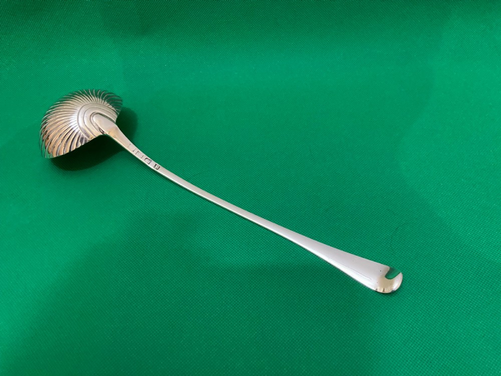 An antique silver punch ladle featuring a deeply fluted shell-shaped bowl and a curved handle with an engraved crest at the terminal. View II