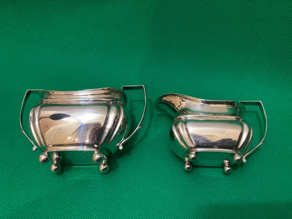 A matching silver cream jug and two-handled sugar bowl featuring gadrooned rims, angular handles, and small ball feet. View III