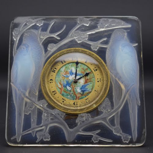 fig 1. A square Rene Lalique Art Deco opalescent glass clock depicting moulded lovebirds amongst branches around a central circular brass dial.