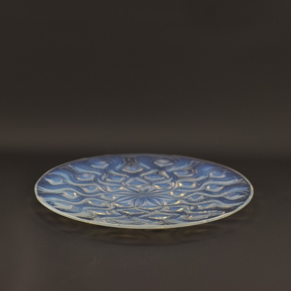 A circular Art Deco opalescent glass plate featuring a repeating pattern of raised oval bulbous motifs emitting a milky blue hue. View II