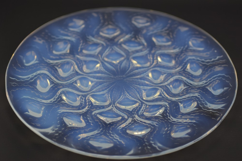 A circular Art Deco opalescent glass plate featuring a repeating pattern of raised oval bulbous motifs emitting a milky blue hue. View III