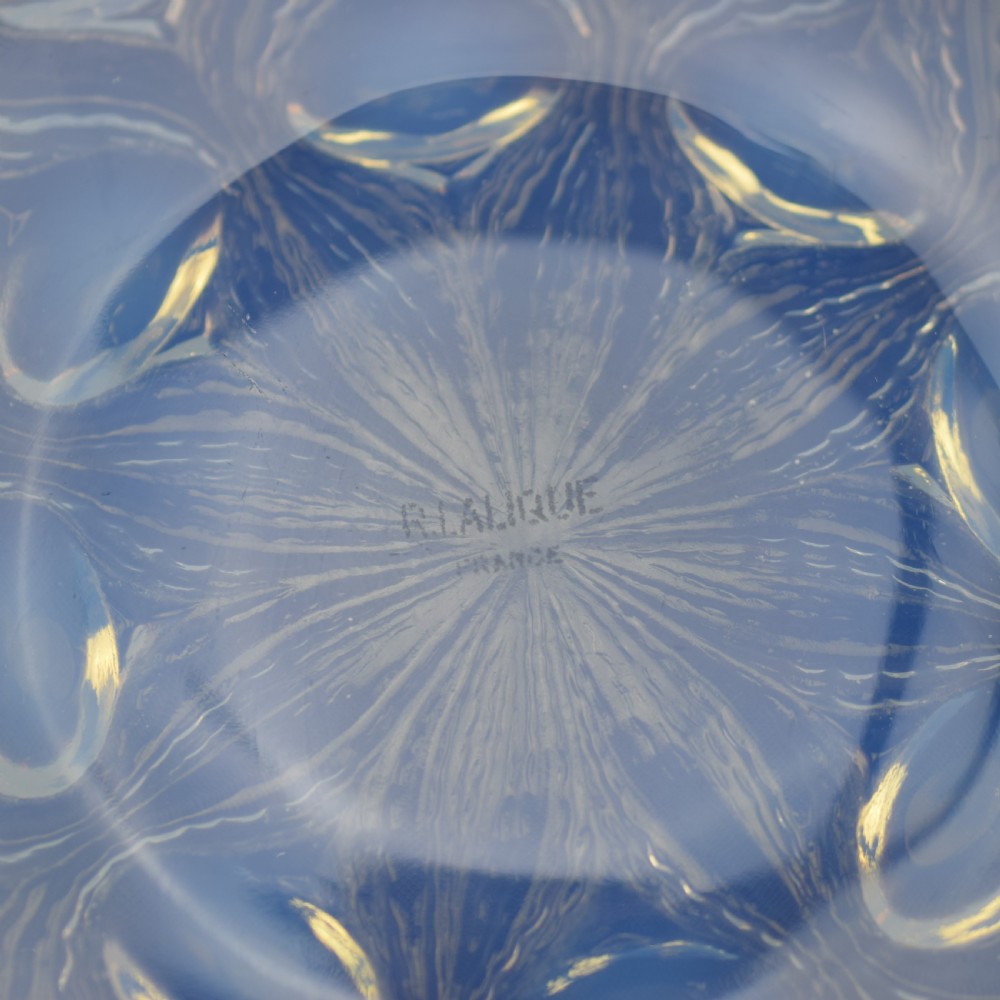 A circular Art Deco opalescent glass plate featuring a repeating pattern of raised oval bulbous motifs emitting a milky blue hue. View V