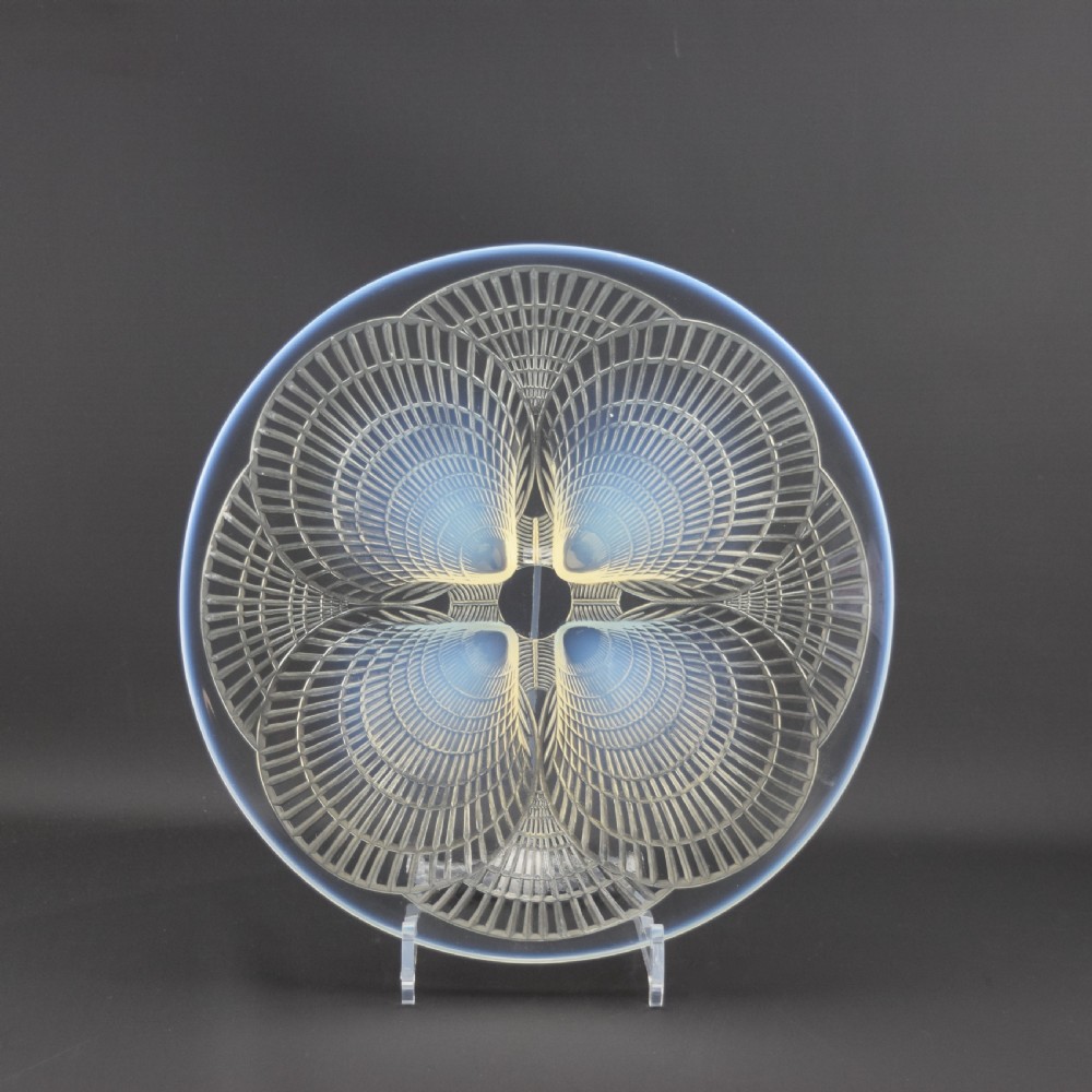 A circular Art Deco opalescent glass plate featuring a relief-moulded four-shell Coquilles design with milky blue tones.
