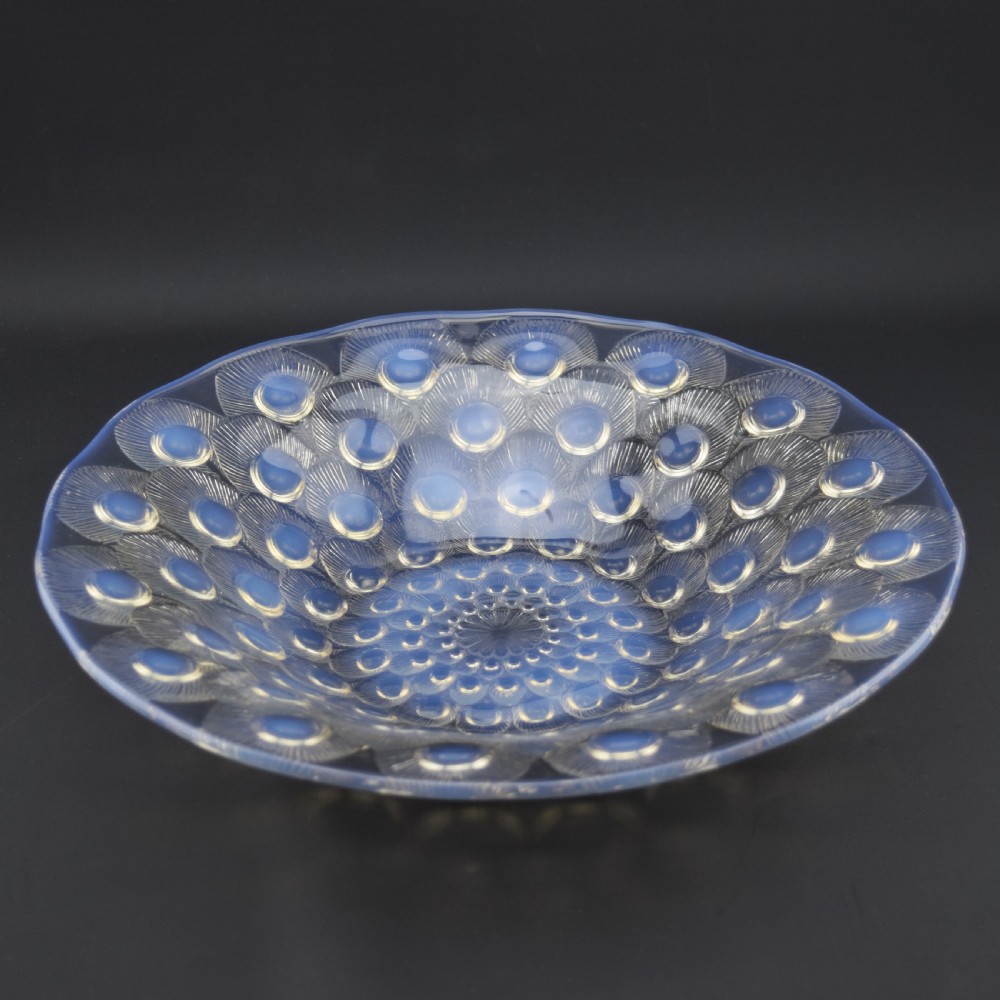 A circular Art Deco opalescent blue glass coupe dish moulded with concentric peacock feather motifs featuring prominent circular cabochons. View II