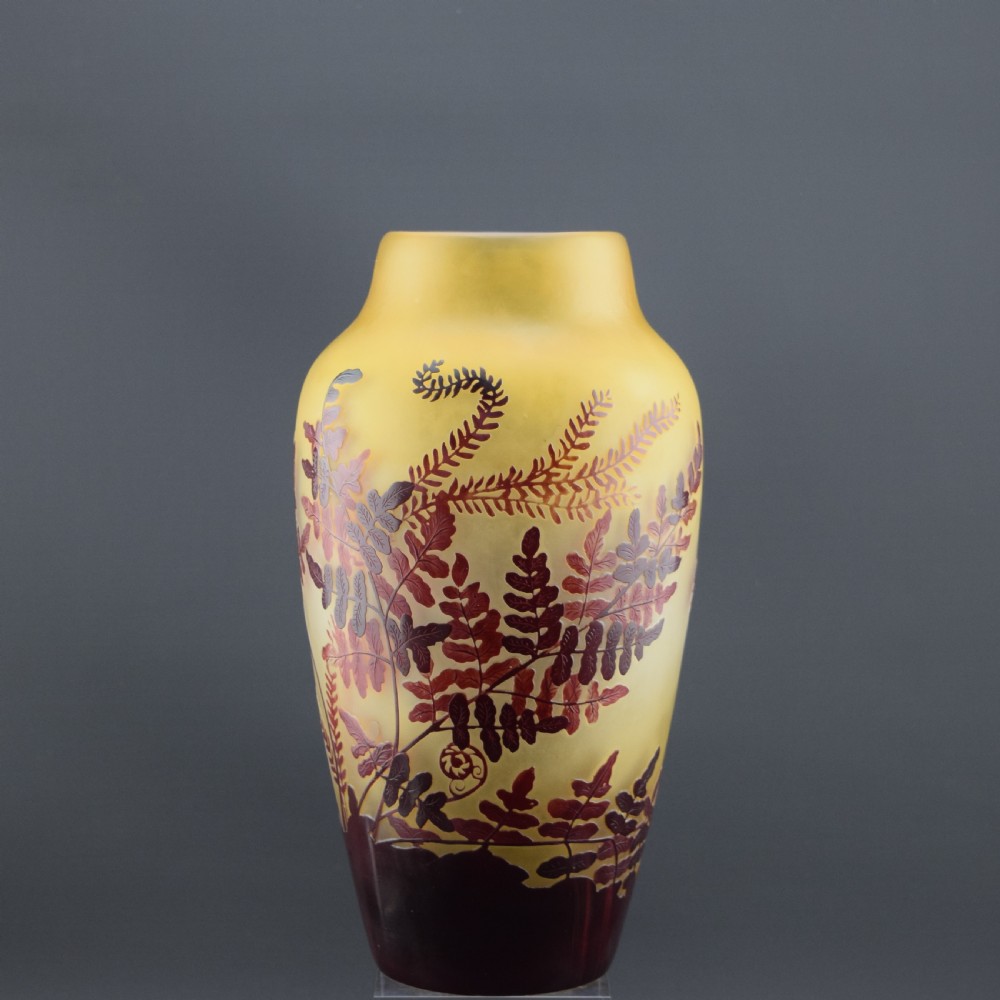 An Art Nouveau cameo glass vase featuring frosted yellow glass acid-etched with dark burgundy fern leaf motifs.