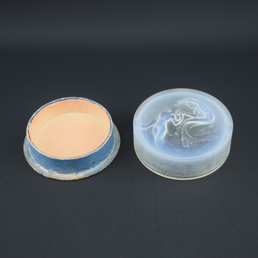 A circular translucent opalescent glass box lid featuring a high-relief moulded depiction of two figures amidst swirling water bubbles. View II