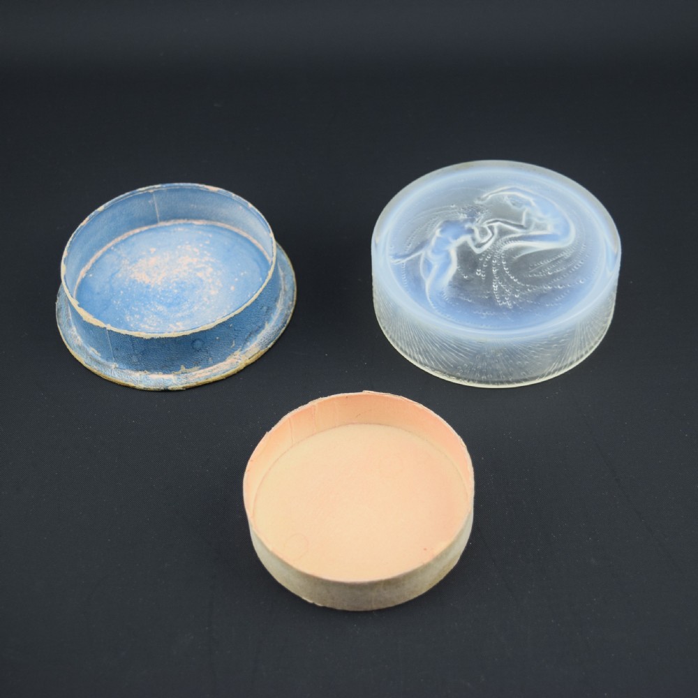 A circular translucent opalescent glass box lid featuring a high-relief moulded depiction of two figures amidst swirling water bubbles. View III