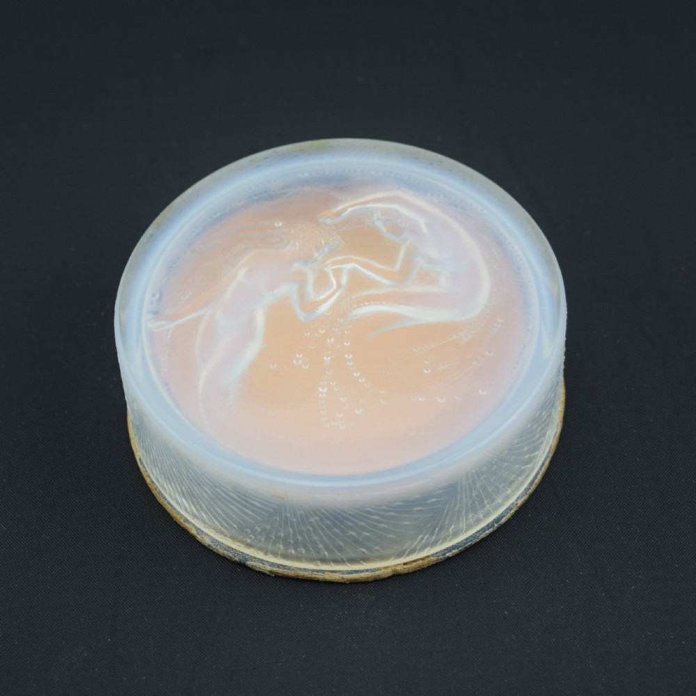 A circular translucent opalescent glass box lid featuring a high-relief moulded depiction of two figures amidst swirling water bubbles. View IV
