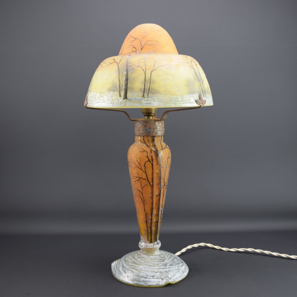 An Art Nouveau Daum enamelled cameo glass table lamp featuring a frosted orange and yellow winter tree landscape.