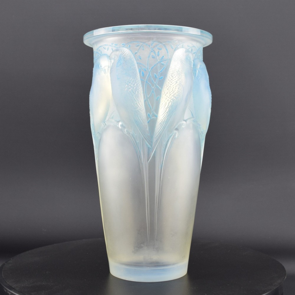 An Art Deco Rene Lalique opalescent glass vase featuring high relief carvings of budgerigars perched on branches with subtle blue staining.