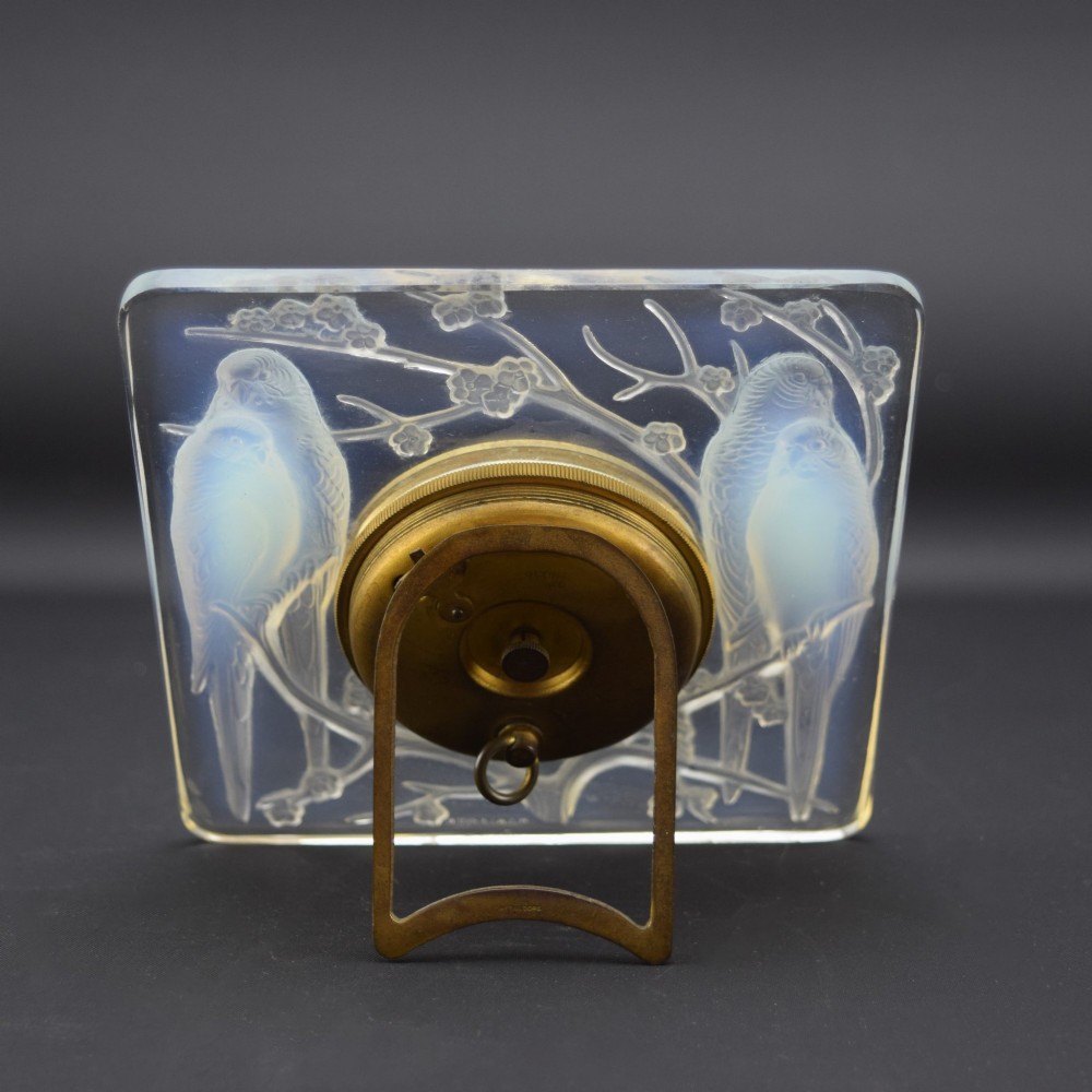 A square Rene Lalique Art Deco opalescent glass clock depicting moulded lovebirds amongst branches around a central circular brass dial. View V