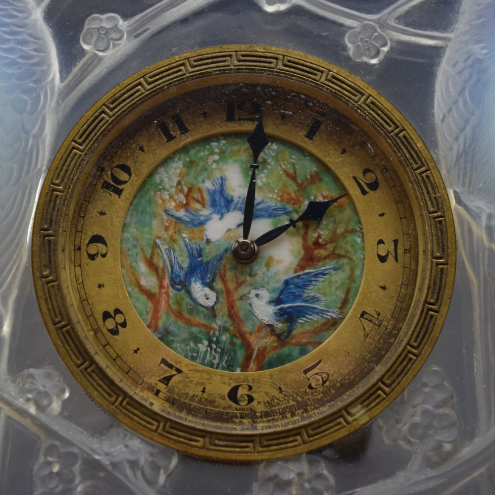 A square Rene Lalique Art Deco opalescent glass clock depicting moulded lovebirds amongst branches around a central circular brass dial. View VII