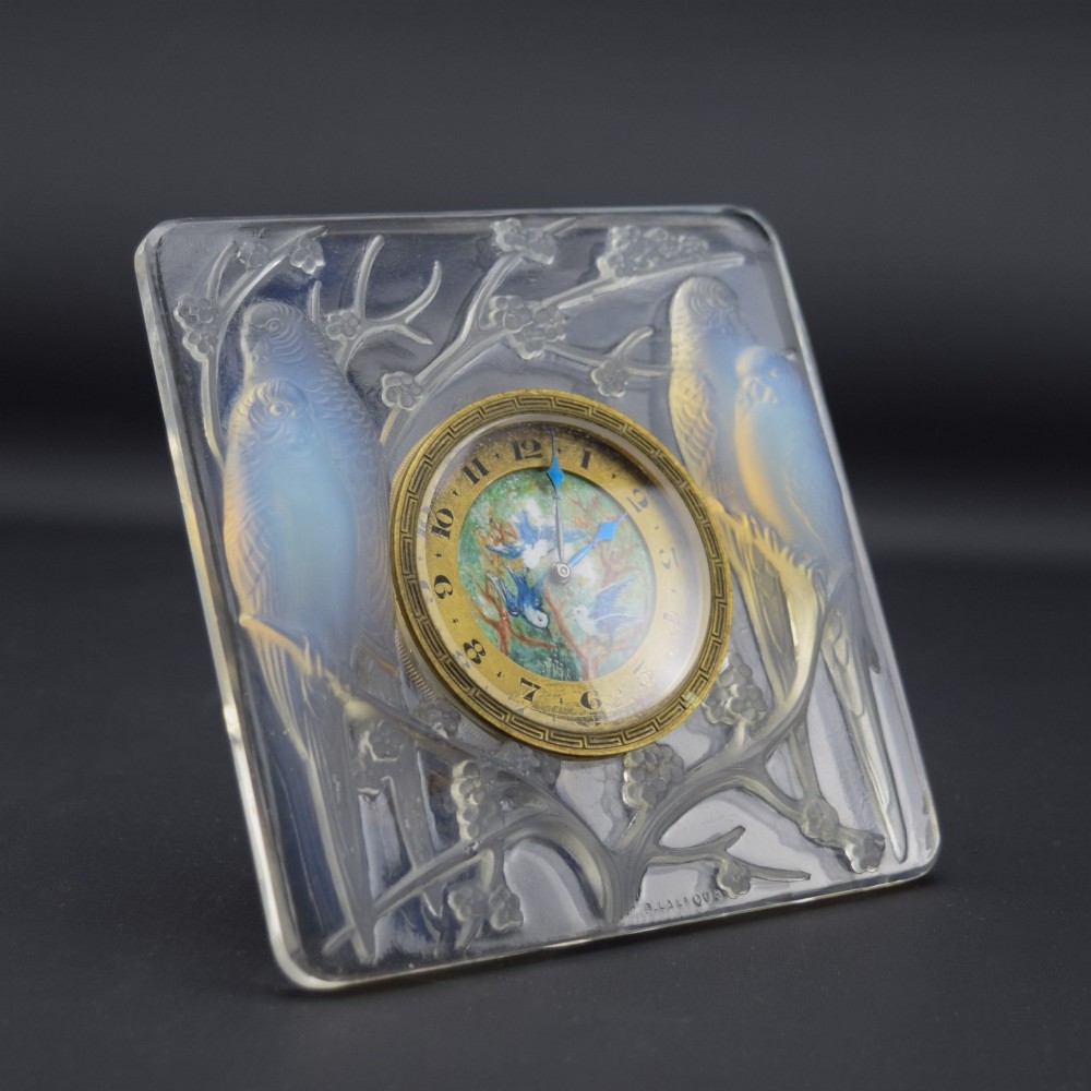 A square Rene Lalique Art Deco opalescent glass clock depicting moulded lovebirds amongst branches around a central circular brass dial. View XII