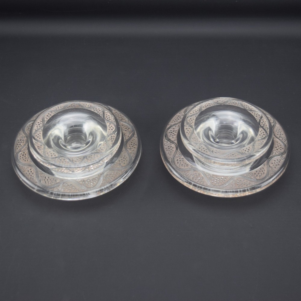 A pair of circular Rene Lalique clear glass Riquewihr candlesticks featuring concentric rings etched with a stylized grapevine motif.