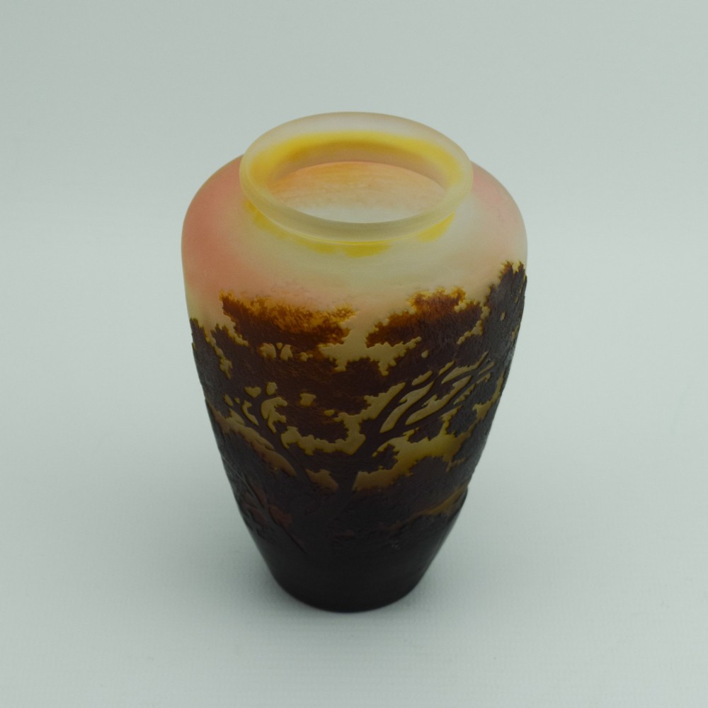 An Art Nouveau cameo glass vase featuring an acid-etched dark brown woodland landscape set against a warm yellow and soft pink background. View II