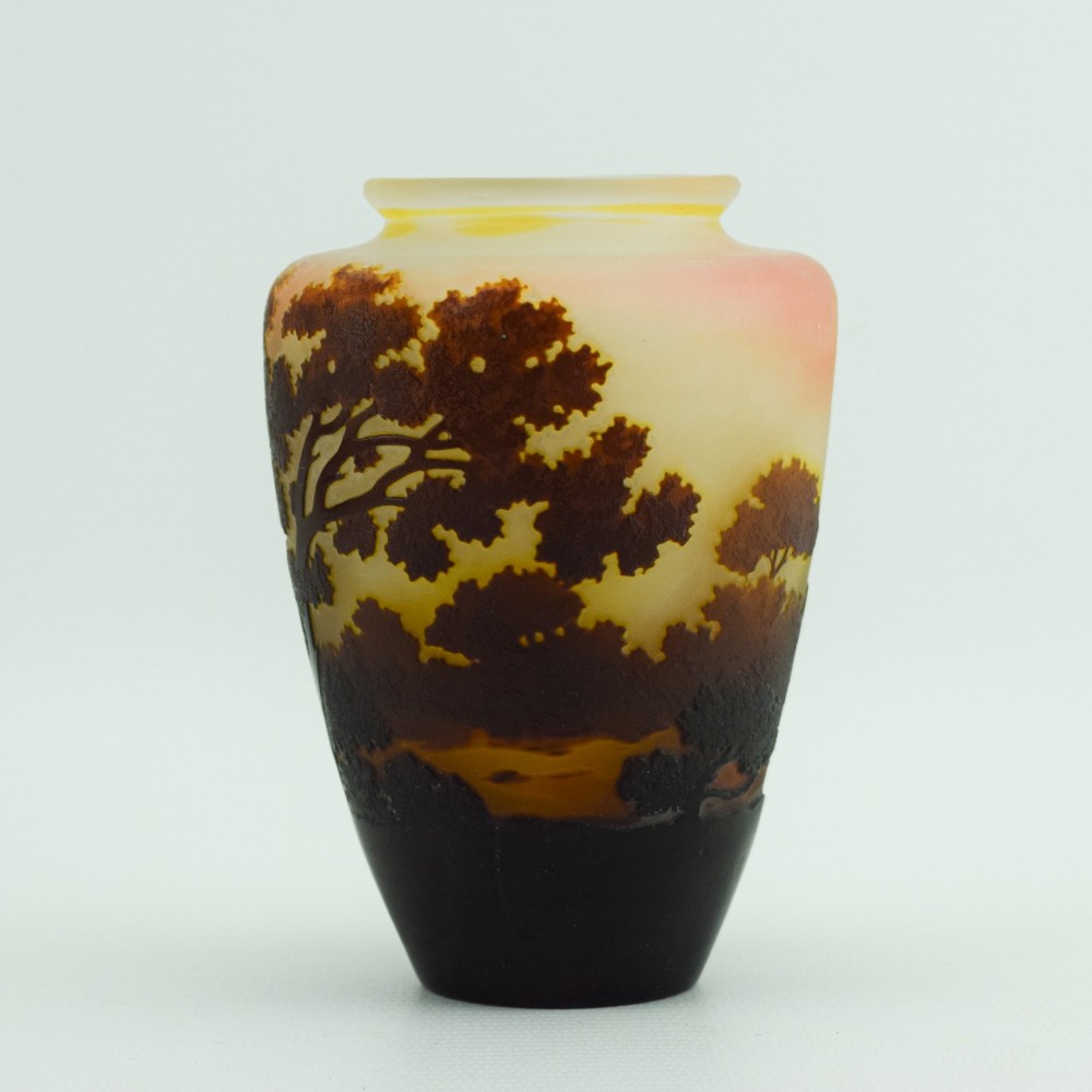 An Art Nouveau cameo glass vase featuring an acid-etched dark brown woodland landscape set against a warm yellow and soft pink background. View IV