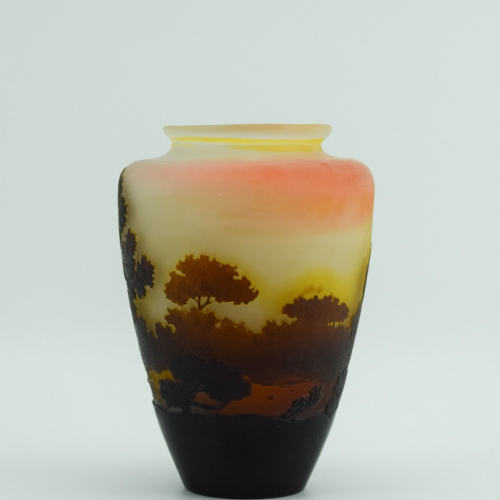 An Art Nouveau cameo glass vase featuring an acid-etched dark brown woodland landscape set against a warm yellow and soft pink background. View V
