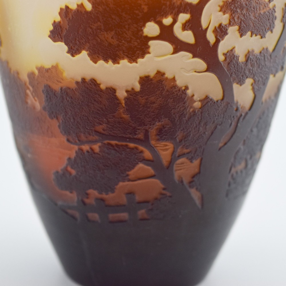 An Art Nouveau cameo glass vase featuring an acid-etched dark brown woodland landscape set against a warm yellow and soft pink background. View IX